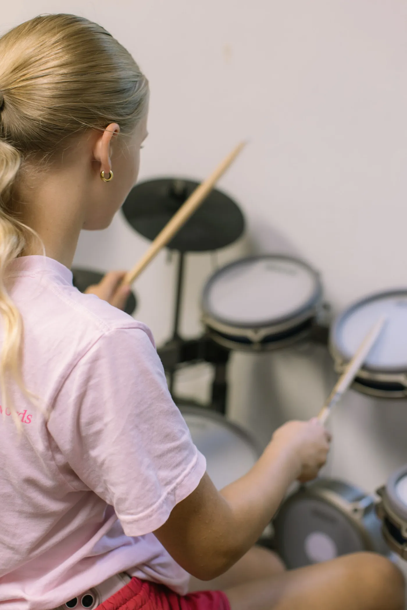 Young drum student playing an electronic drum kit during a lesson at LyriCo