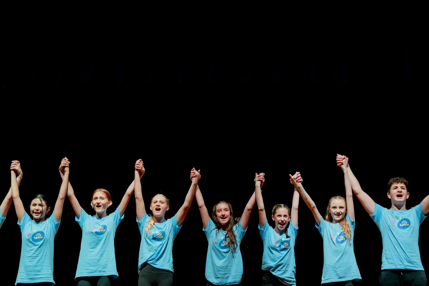 LyriCo performers holding hands for a curtain call on stage in Gainesville