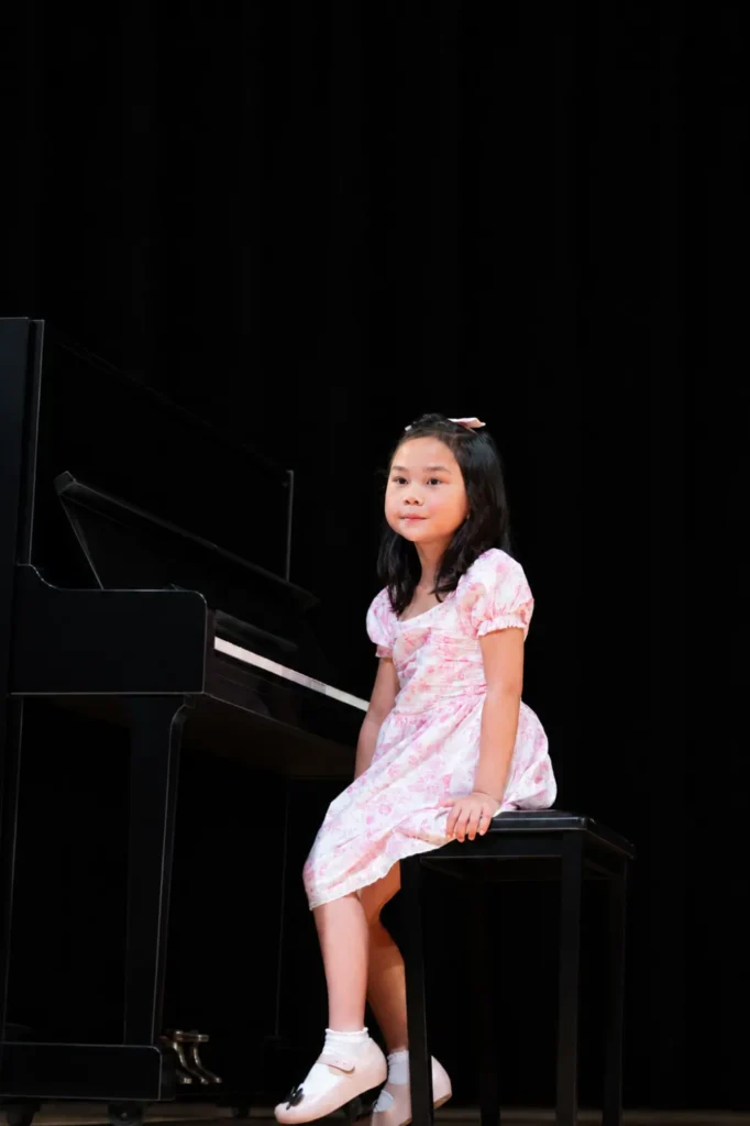Young piano student seated at the piano on stage at a LyriCo Conservatory recital in Gainesville